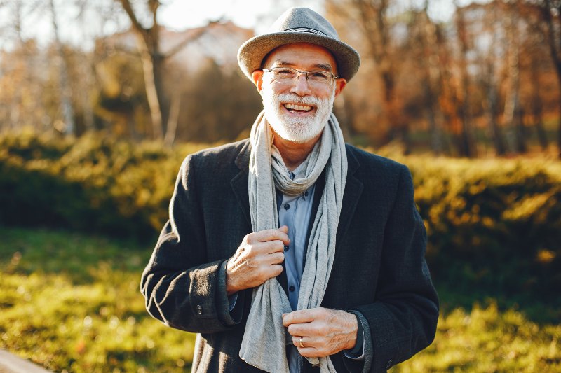 Handsome grandfather in a autumn park. Old man in a gray jacket and hat.