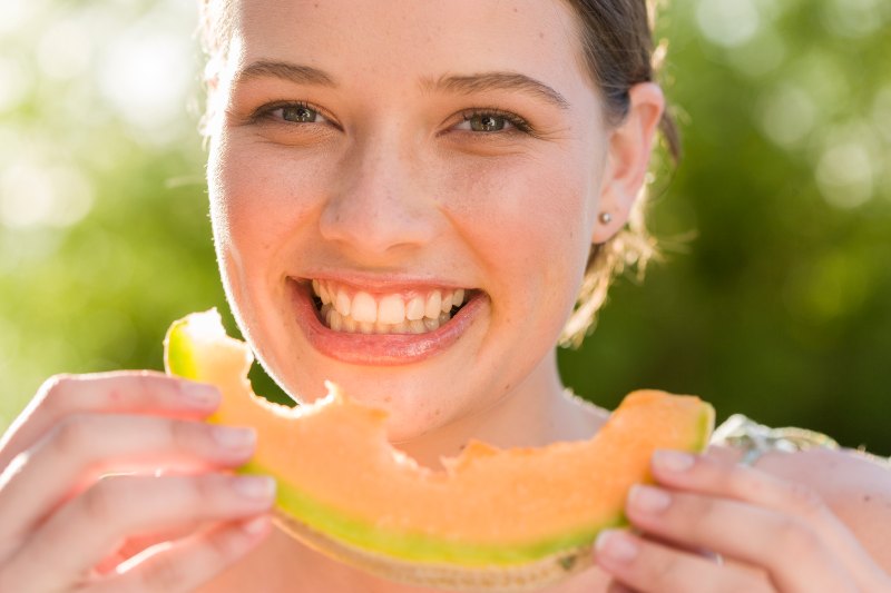 portrait-smiling-woman-eating-melon-outdoors